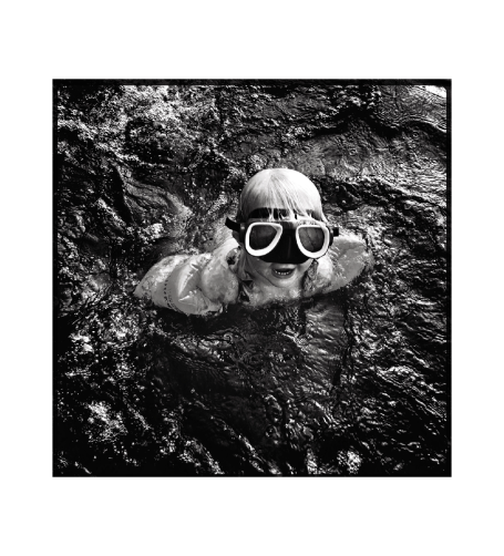 En person med simglasögon som simmar i vatten.